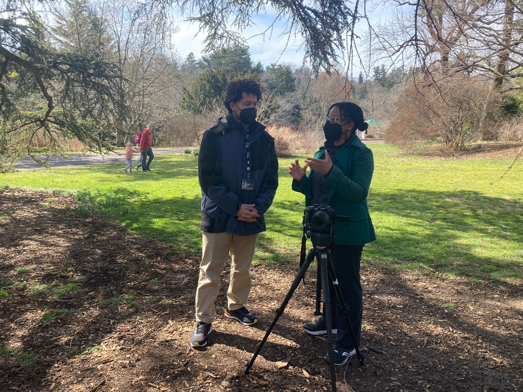 Monique talking with colleague and director Juan Castillo outdoors at arboretum in front of camera station.